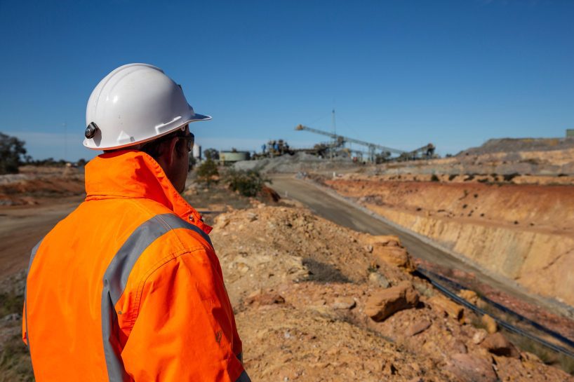 Male in front of a mine portal road, with minehead in background in NSW Australia