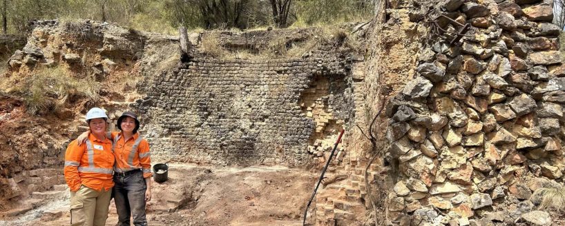 Two females at an archaeology work site with arms around shoulder