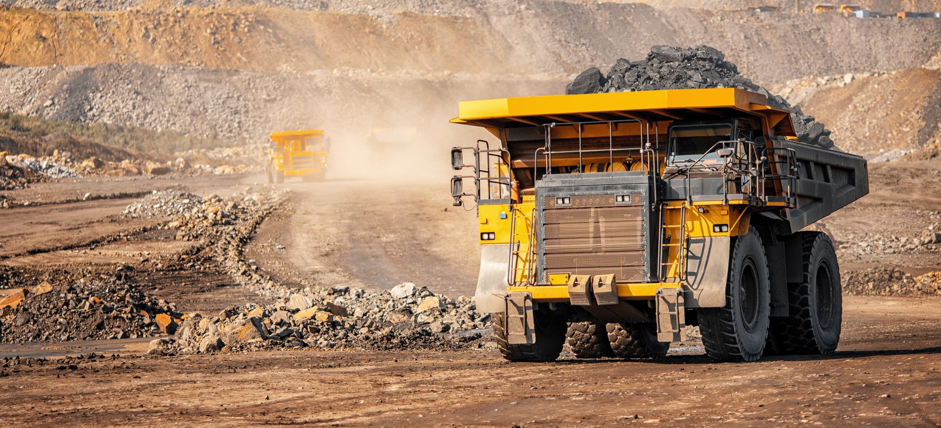 Big yellow mining truck driving through an open cut mine